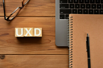 On the table there is a word cube lined UXD with laptop computers and glasses. It is an abbreviation for the word User experience design.