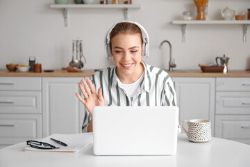 Poster - Young woman with laptop video chatting in kitchen