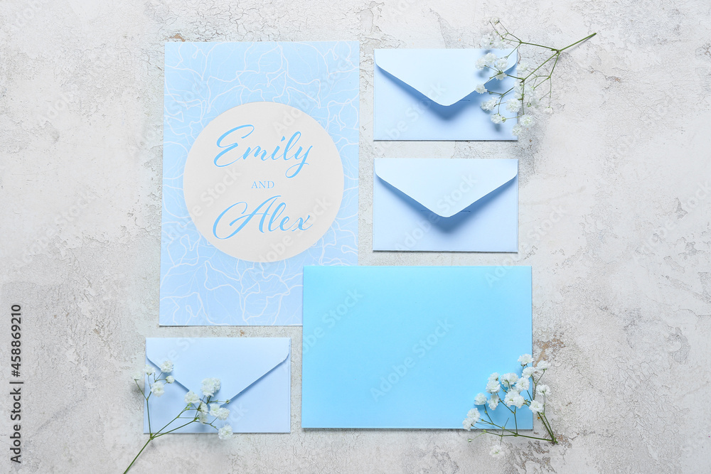 Card with text EMILY & ALEX, envelopes and flowers on light background