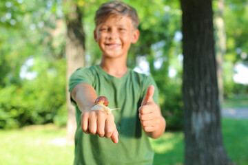 Poster - Happy little boy with snail outdoors