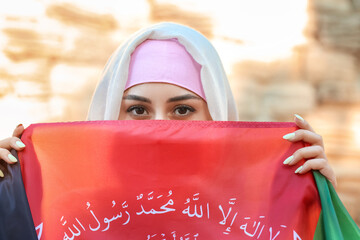 Muslim woman with flag of Afghanistan on city street