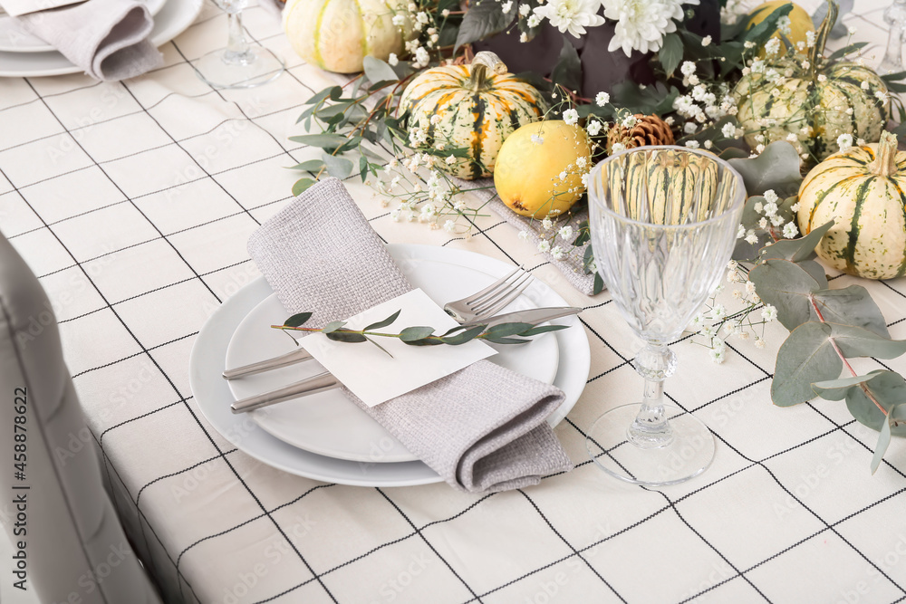 Modern table setting with card and autumn decor in restaurant