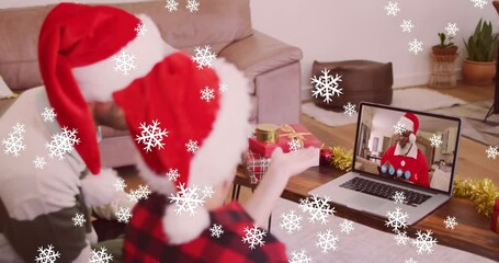 Canvas Print - Animation of snow falling over smiling father and son in santa hats on laptop video call with family