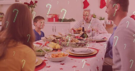 Canvas Print - Animation of candy canes falling over smiling caucasian family having dinner