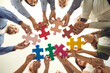 © Studio Romantic - Group of young and mature people making circle of colorful jigsaw puzzle parts, low angle shot from below. Happy business team enjoying teamwork, finding professional solution, starting new enterprise
