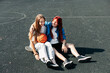 © Sviatlana - A couple of teenage girls on a sports street court with a basketball lifestyle relax after a game and talk. The concept of sports and a healthy lifestyle