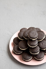 Wall Mural - Homemade Oreos on a pink plate on a gray background, side view. Space for text.