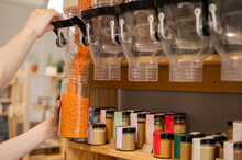 A Man Fills A Jar With Red Lentils. Selling Bulk Goods By Weight In An Eco Store. Trade Concept Without Plastic Packaging