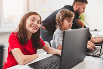 Wall Mural - happy schoolgirl with laptop in classroom
