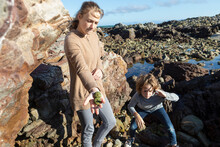 A Brother And Sister On The Beach Among Rock Pools, Showing Shell Finds, De Kelders, Western Cape, South Africa.