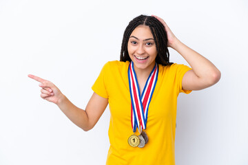 Poster - Teenager girl with braids and medals over isolated pink background surprised and pointing finger to the side