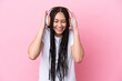 © luismolinero - Teenager girl with braids over isolated pink background listening music