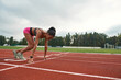 © Svitlana - Professional young female runner in sportswear starting race on track field at stadium