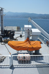 Sticker - Vertical shot of a white ship in the blue calm sea on the background of mountains under a clear sky