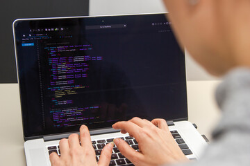 Wall Mural - a programmer coding on a laptop in the workplace