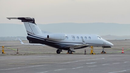 Wall Mural - Side view of white twin-engined cantilever monoplane with low-positioned, swept wings, turbofan powered business jet on the airport. Modern technology in fast transportation, travel aviation.