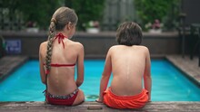 Back View Of Little Romantic Boy And Girl Sitting At Poolside Sunbathing At Summer Resort. Shy Caucasian Children Resting On Sunny Day Outdoors. Romance And Love Concept