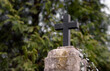 A close-up of the cross. Catholic cemetery. Blurred background with trees. Candles on graves.