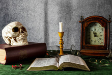 Vanitas Style Still Life With Skull On Bible Old Clock And Burned Out Candle