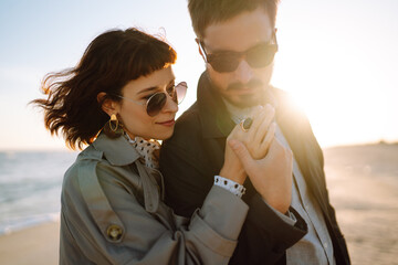 Wall Mural - Fashion couple enjoying each other on beach during autumn sunny day. Travel, weekend, relax .and lifestyle concept. 