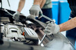 © Drazen - Close-up of auto mechanic uses wrench while working on car engine at repair shop.