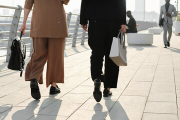 Horizontal back view shot of unrecognizable women wearing elegant formal clothes strolling down street somewhere in modern city