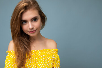 Wall Mural - Closeup photo of young cute beautiful dark blonde woman with sincere emotions isolated on background wall with copy space wearing yellow dress. Positive concept