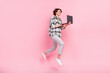 © deagreez - Full body profile side photo of young woman happy positive smile jump use laptop isolated over pink color background