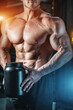 © goami - closeup of muscular athlete holding black container with protein whey supplement