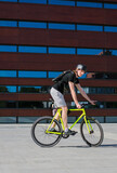 Fototapeta Londyn - young men in a helmet on a yellow bike - Fxed gear - in the city, on the background of the building