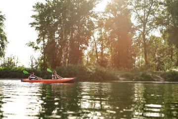 Wall Mural - Two young friends looking cheerful while boating together on a lake surrounded by peaceful summer nature