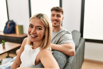 Poster - Young caucasian couple smiling happy sitting on the sofa at home.