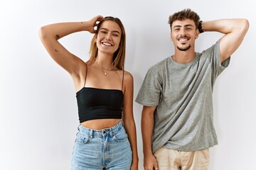 Wall Mural - Young beautiful couple standing together over isolated background smiling confident touching hair with hand up gesture, posing attractive and fashionable