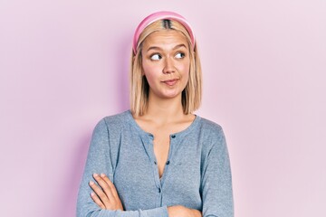 Poster - Beautiful blonde woman standing over pink background smiling looking to the side and staring away thinking.