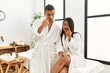 Young latin couple wearing towel standing at beauty center pointing to the eye watching you gesture, suspicious expression