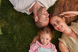 © Svitlana - Top view of happy young parents with little daughter lying on green grass in summer park