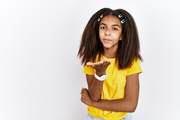 Poster - Young african american girl standing over white isolated background looking at the camera blowing a kiss with hand on air being lovely and sexy. love expression.