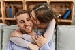© Krakenimages.com - Young caucasian couple sitting on the sofa hugging and kissing at home.