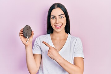 Canvas Print - Beautiful woman with blue eyes holding pumice stone smiling happy pointing with hand and finger