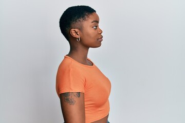 Sticker - Young african american woman wearing casual orange t shirt looking to side, relax profile pose with natural face with confident smile.