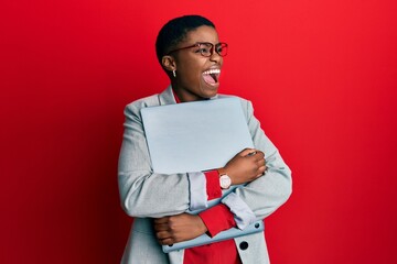 Canvas Print - Young african american businesswoman holding laptop angry and mad screaming frustrated and furious, shouting with anger. rage and aggressive concept.