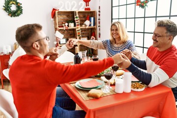 Sticker - Group of middle age caucasian family having christmas dinner and praying for food sitting on the table at home.