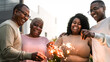 © Alessandro Biascioli - Happy African family celebrating holidays with sparklers fireworks at house party