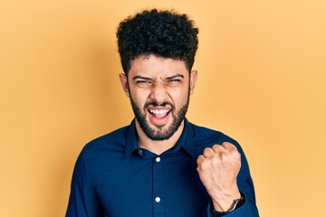 Canvas Print - Young arab man with beard wearing casual shirt angry and mad raising fist frustrated and furious while shouting with anger. rage and aggressive concept.