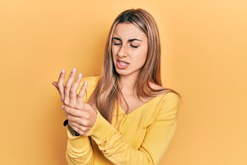 Canvas Print - Beautiful hispanic woman wearing casual yellow sweater suffering pain on hands and fingers, arthritis inflammation