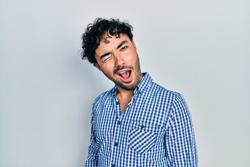 Canvas Print - Young hispanic man wearing casual clothes winking looking at the camera with sexy expression, cheerful and happy face.