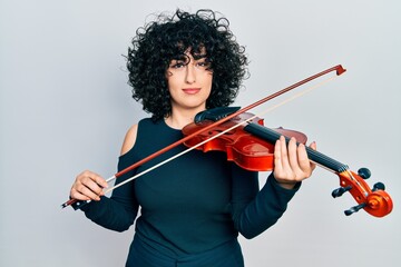 Poster - Young middle east woman playing violin relaxed with serious expression on face. simple and natural looking at the camera.