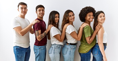 Poster - Group of young friends standing together over isolated background looking to side, relax profile pose with natural face and confident smile.