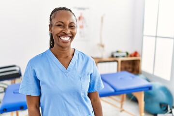 Canvas Print - Black woman with braids working at pain recovery clinic winking looking at the camera with sexy expression, cheerful and happy face.