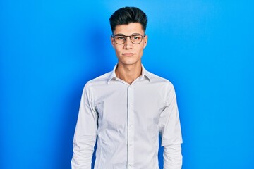 Wall Mural - Young hispanic man wearing casual clothes and glasses with serious expression on face. simple and natural looking at the camera.